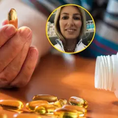 Dłoń trzyma kapsułkę witaminy D. Obok leży buteleczka i kilka kapsułek. W tle uśmiechnięta farmaceutka. Dowiedz się, z czym nie łączyć witaminy D.
