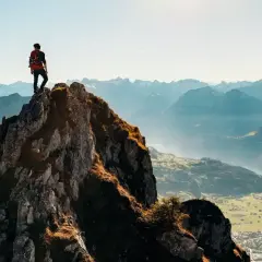 Alpinista na szczycie skalistej góry, podziwiający panoramę. Czy wejście na rysy jest trudne? Widok zapiera dech w piersiach, ale droga na górę wymaga wysiłku.