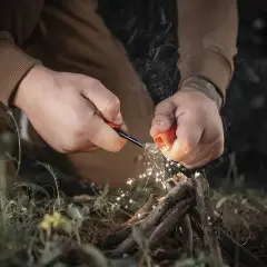 Ręce rozpalają ognisko krzesiwem, iskry lecą na patyki. To sztuka przetrwania, esencja bushcraftu.