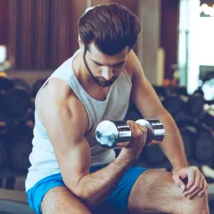 Mężczyzna ćwiczy biceps z hantlem w siłowni.