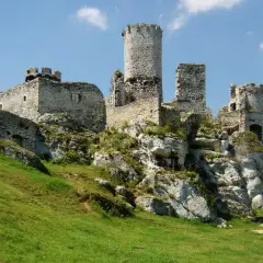 Ruiny zamku na wapiennym wzgórzu, część Szlaku Orlich Gniazd. Zielona trawa i błękitne niebo.