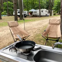 Dwie składane krzesła, kuchenka z patelnią i zlew to idealne rzeczy, co zabrać na wakacje pod namiotem.