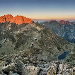 Zachód słońca nad najwyższym szczytem w Tatrach. Skaliste zbocza i górskie jeziora w blasku złotej godziny.