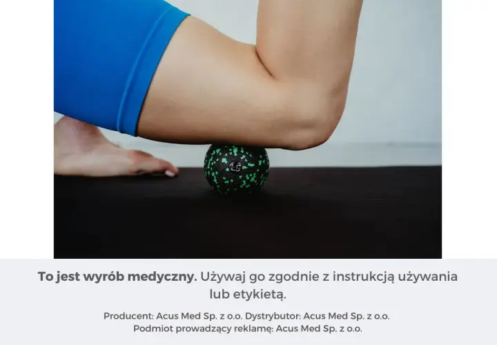 Masażysta ugniata czworogłowy uda za pomocą zielonej piłeczki do masażu na czarnej macie.