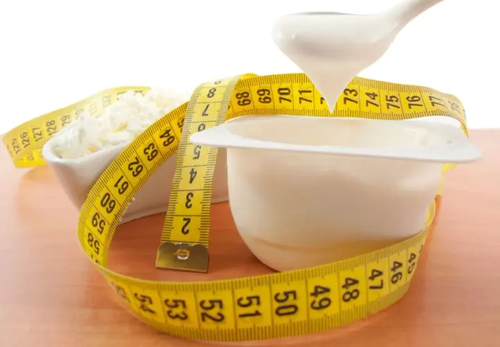Biały jogurt i twaróg owinięte miarką. Czy od białka się tyje? Zdrowa dieta to klucz do sukcesu.