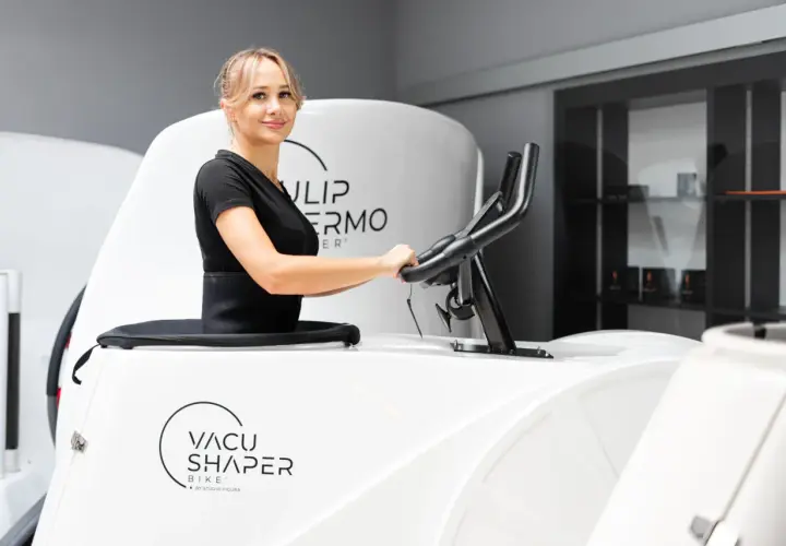 Kobieta ćwiczy na rowerze Vacu Shaper, by osiągnąć wymarzone efekty.
