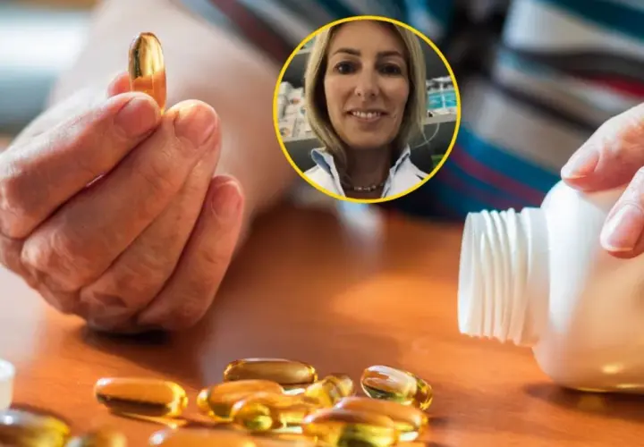 Dłoń trzyma kapsułkę witaminy D. Obok leży buteleczka i kilka kapsułek. W tle uśmiechnięta farmaceutka. Dowiedz się, z czym nie łączyć witaminy D.