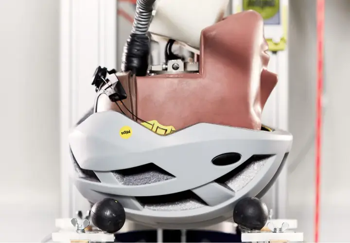 Test kasku rowerowego z technologią Mips. Manekin głowy w szarym kasku, przygotowany do symulacji uderzenia.