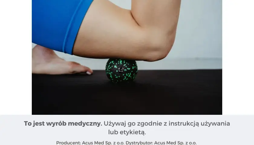 Masażysta ugniata czworogłowy uda za pomocą zielonej piłeczki do masażu na czarnej macie.