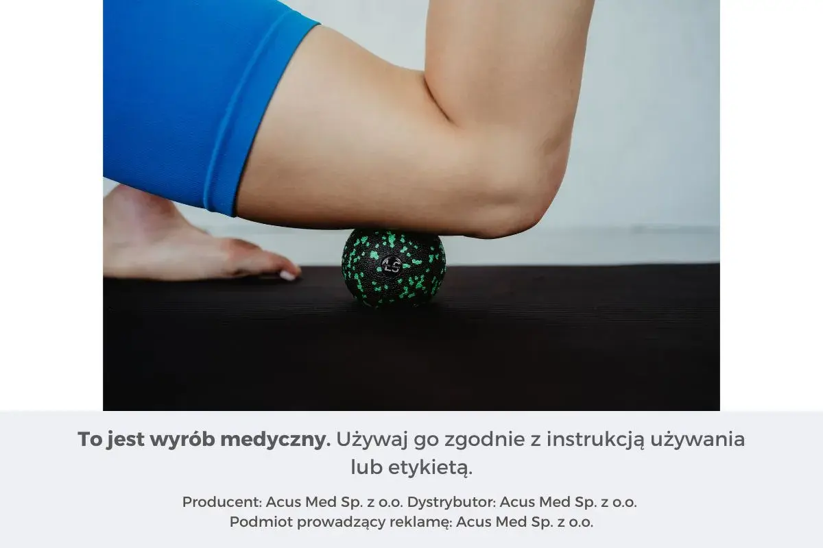 Masażysta ugniata czworogłowy uda za pomocą zielonej piłeczki do masażu na czarnej macie.