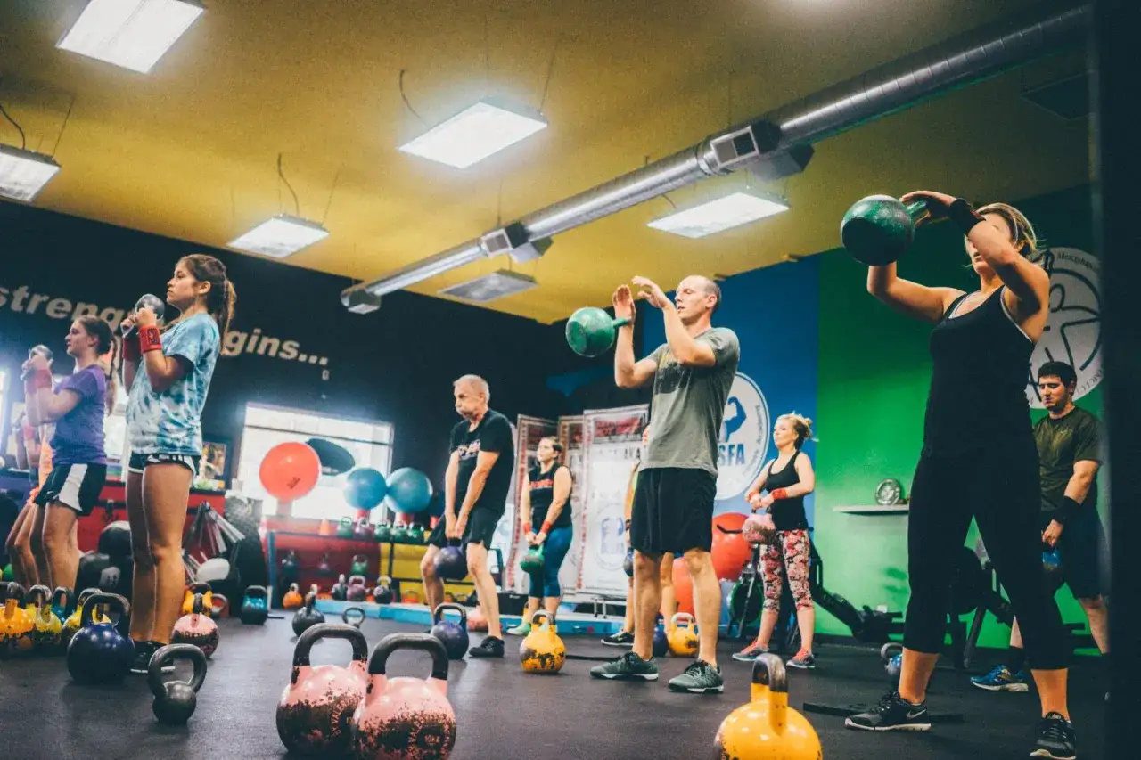 Grupa osób ćwiczy z kettlebellami, wykonując trening interwałowy.